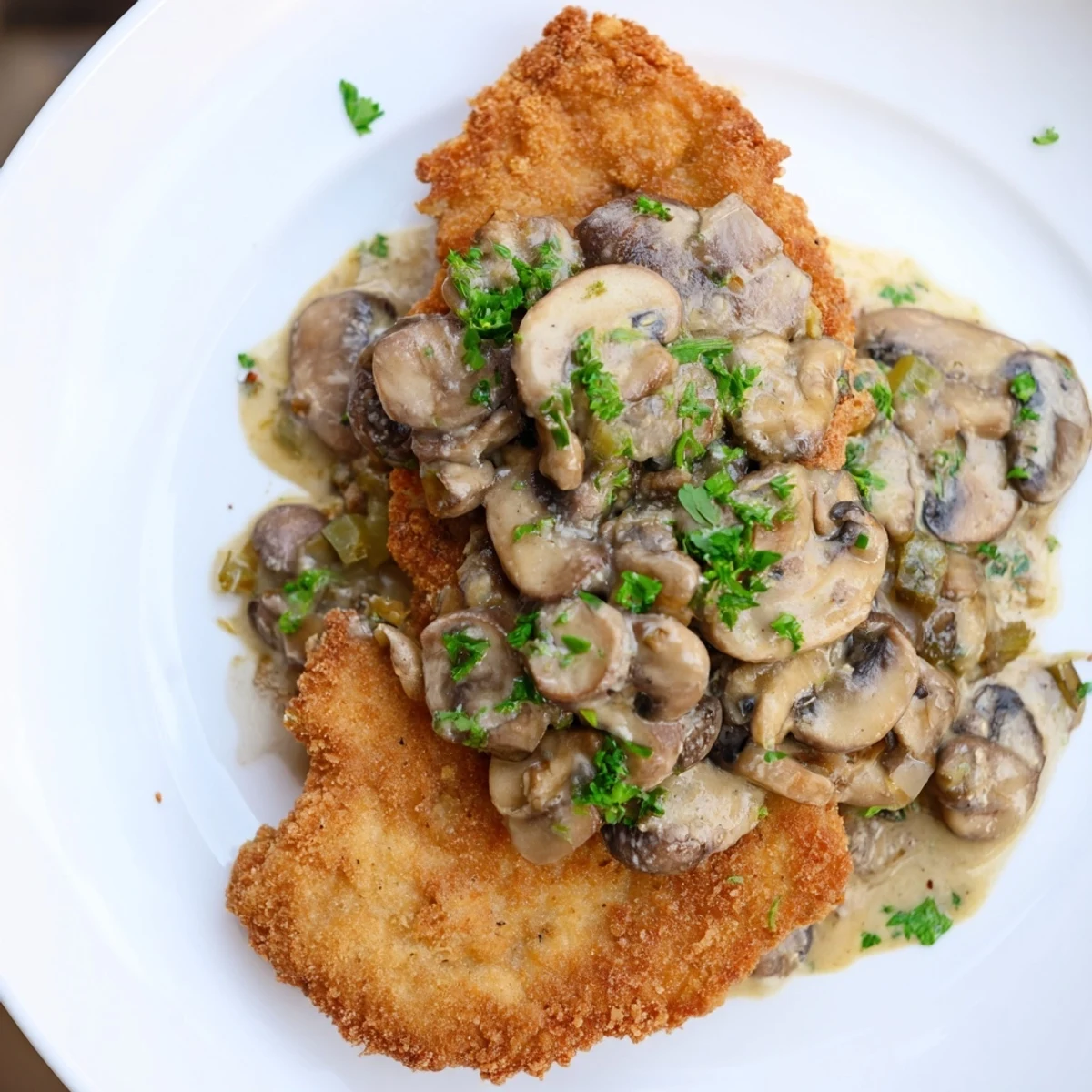 Golden-brown Jaeger Schnitzel rests, smothered in rich mushroom gravy, ready to be enjoyed.