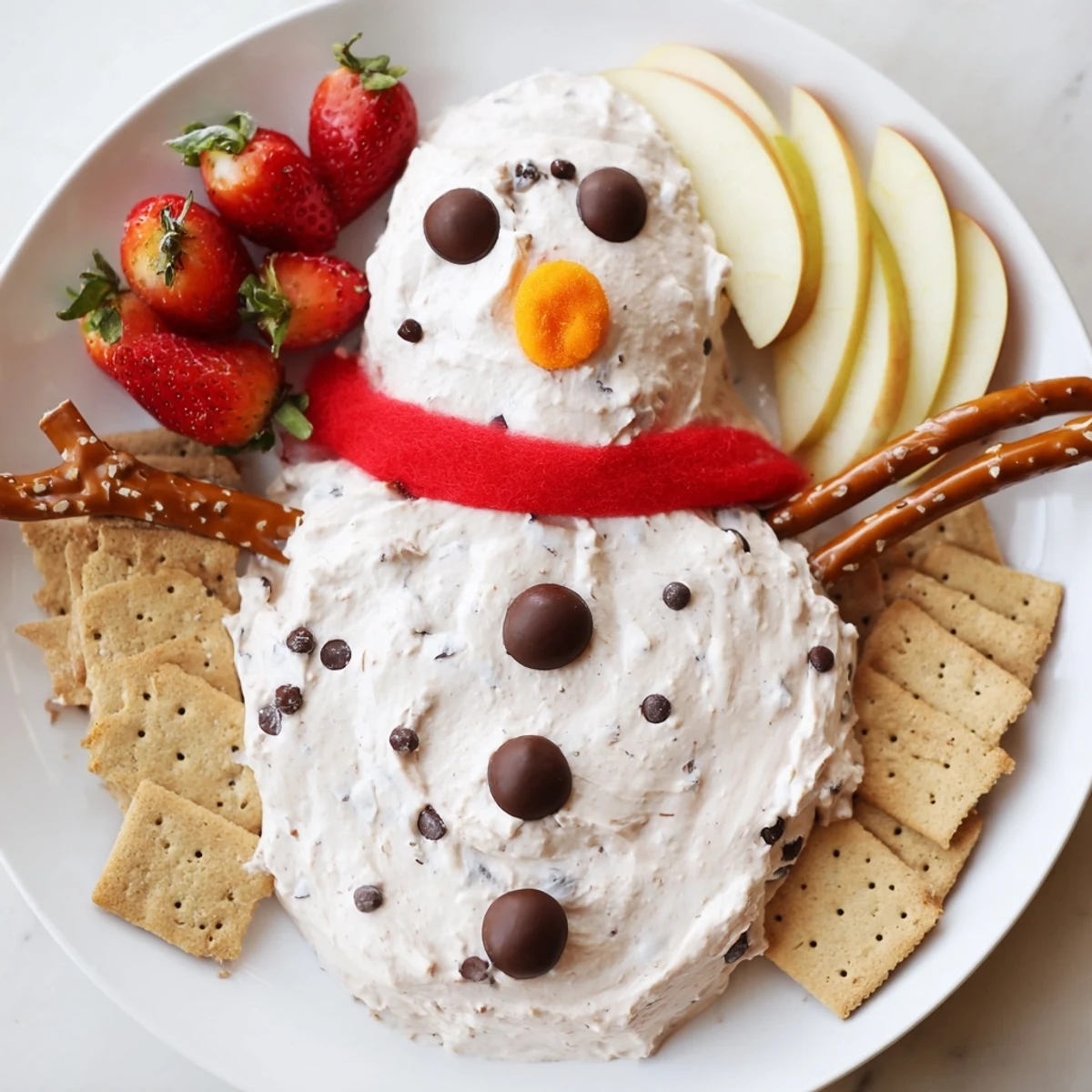 A festive hot cocoa dip snowman served with dippers like graham crackers, a fun dessert idea.