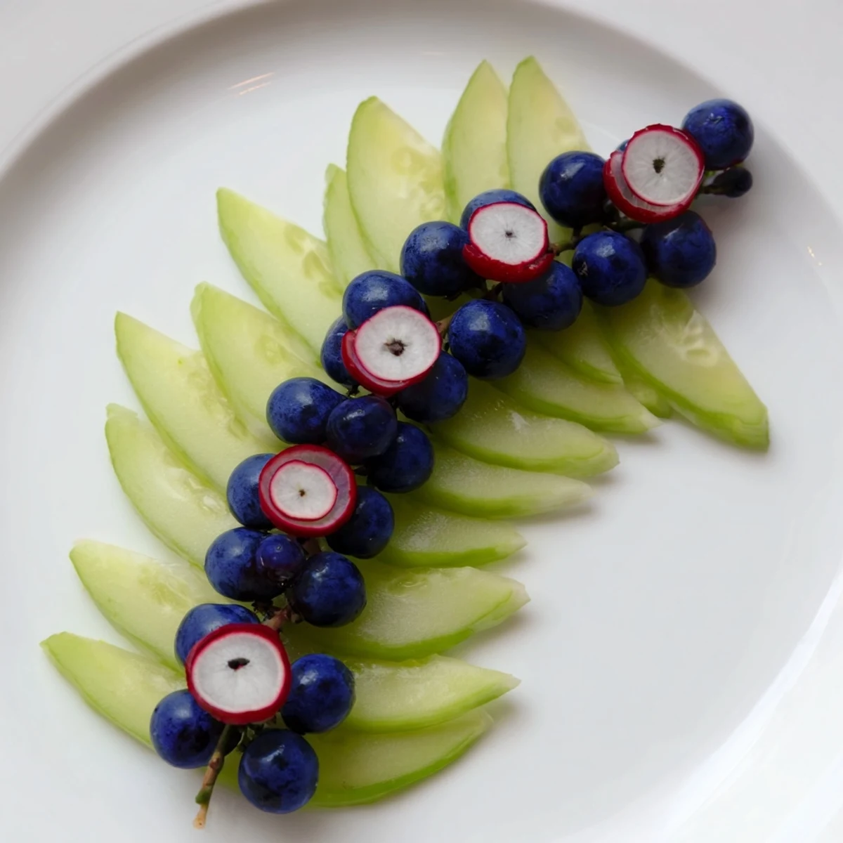 A visually stunning Peacock Tail appetizer featuring a cucumber fan, grapes, and radish accents.