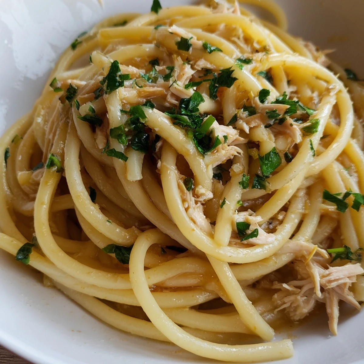 A close-up of Simple Garlic Butter Bucatini shows glistening pasta and tender chicken; ready to eat.