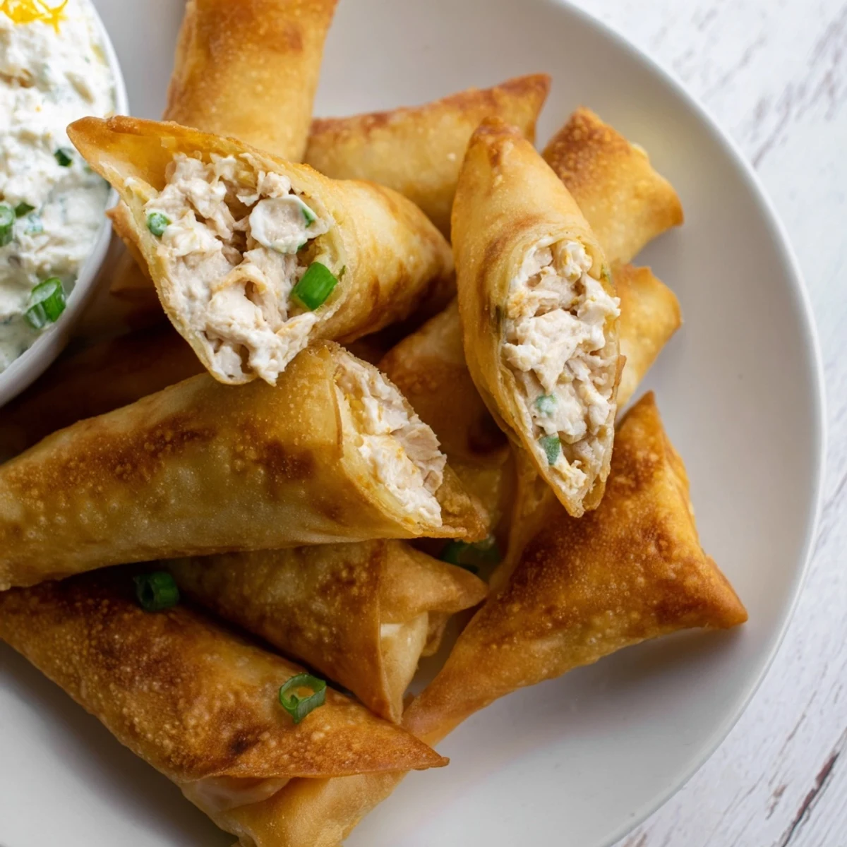 Crispy golden air fryer lumpia chips alongside a creamy chicken cream cheese dip, a delicious appetizer.