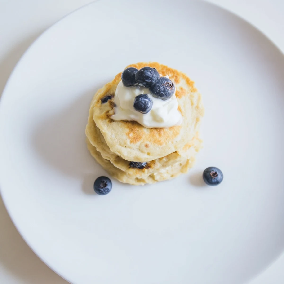 Stack of light, airy protein banana pancakes with visible bubbles, cooked to perfection on a skillet.