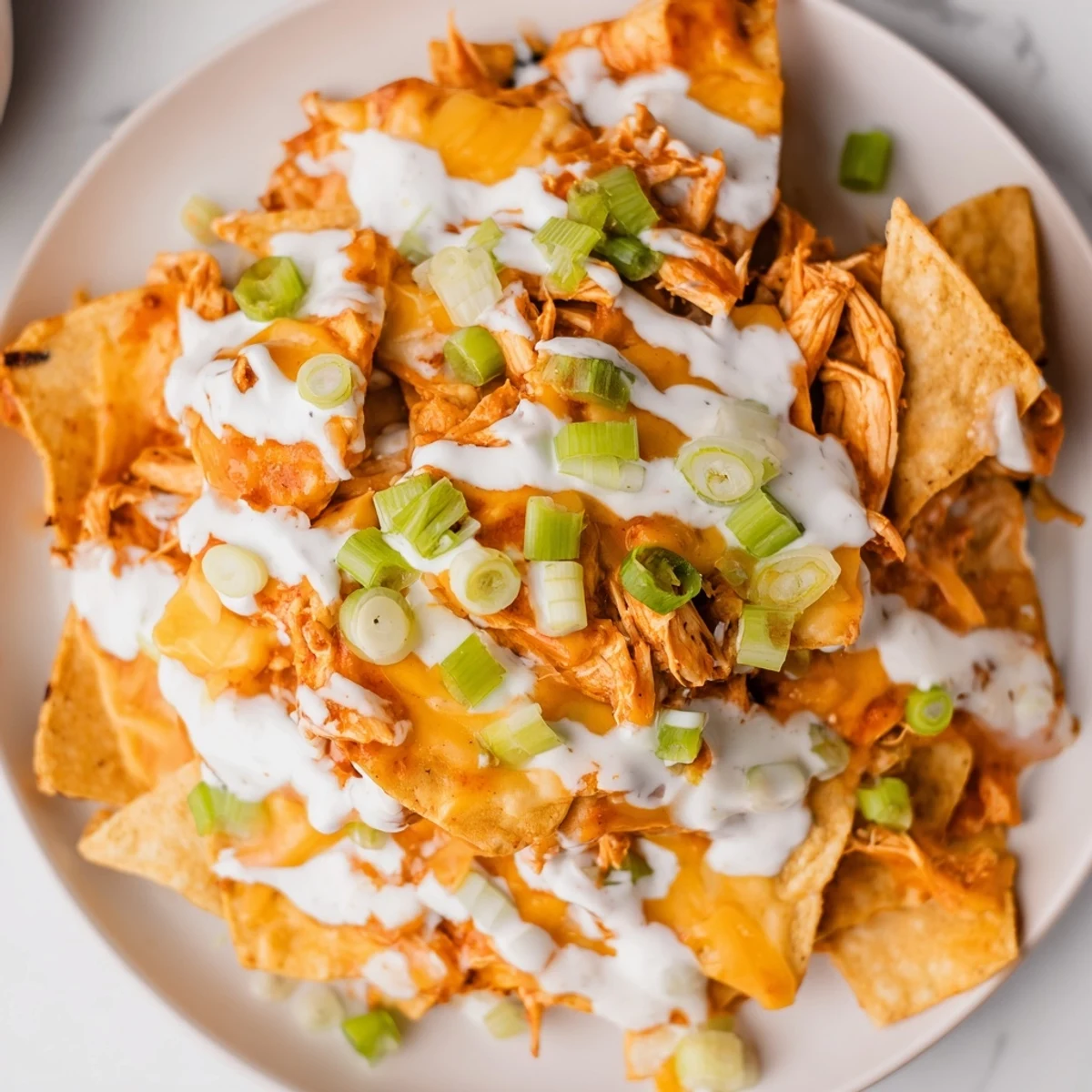 Geröstete Tortilla-Chips mit würdiger Buffalo-Hähnchen-Belag, geschmolzenem Käse und grünem Zwiebel-Topping.