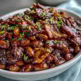 2. A close-up of Summer BBQ Baked Beans with Brown Sugar and Bacon, showcasing tender beans in a glossy, caramelized glaze topped with golden bacon.  