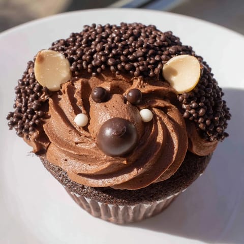 Adorable hedgehog cupcake tower, frosted with chocolate buttercream, ready for a kids' party, is shown.