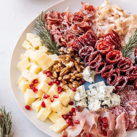 This festive Winter Forest Meat and Cheese Charcuterie Scene, showcasing various meats, cheeses, and garnishes, looks delicious.