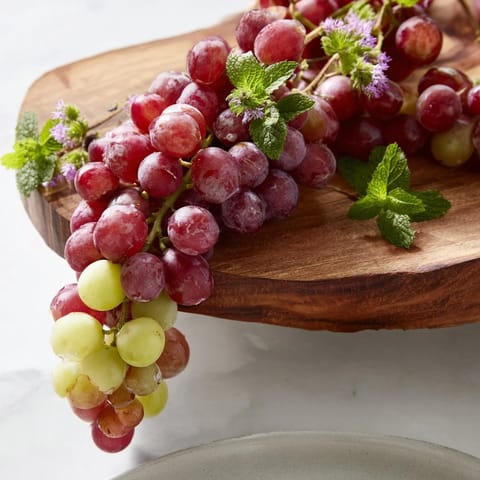Juicy red and green grapes cascade over the serving board, perfect for a refreshing snack.