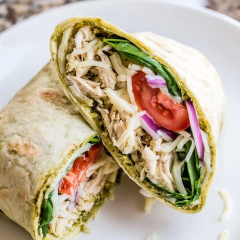 A close-up view of a delicious Pesto Chicken Wrap, showing layers of chicken and vibrant pesto.
