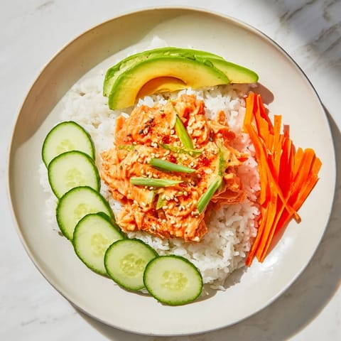 Flaky spicy canned salmon sits atop rice in this flavorful bowl, ready to eat.