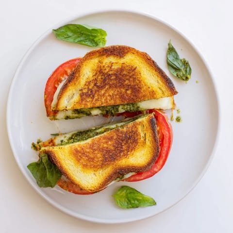 Kaprese-Pesto-Grilled Cheese Sandwich, golden getoastet mit geschmolzenem Mozzarella und saftigen Tomatenscheiben.