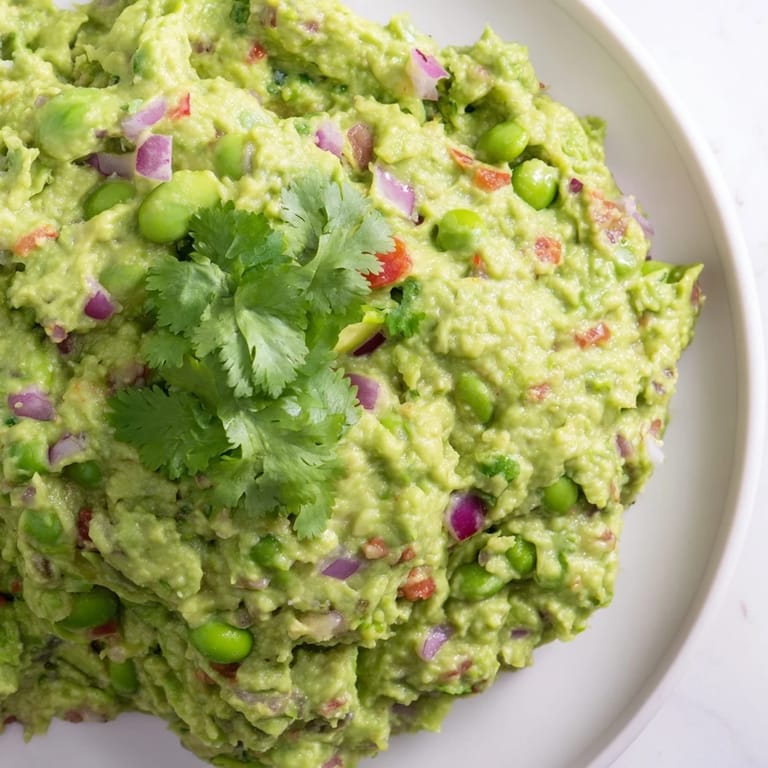 Freshly made edamame guacamole garnished with cilantro, perfect for dipping tortilla chips or vegetables.