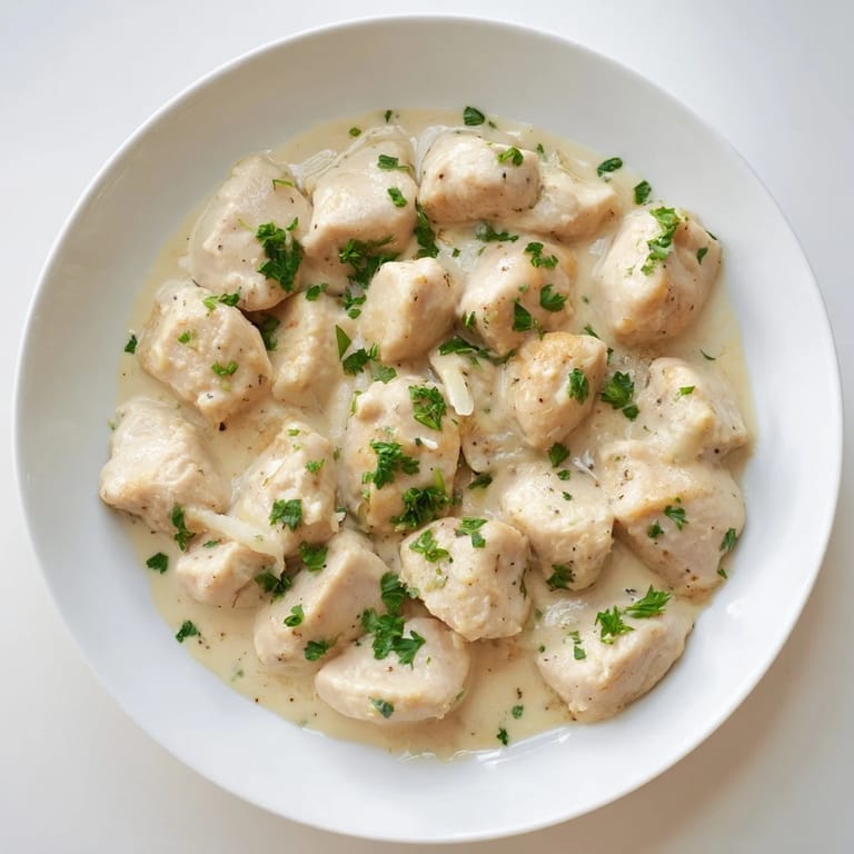 Goldbraune Hähnchenstücke in cremiger Knoblauchsoße, serviert über Beilagen für ein wohlschmeckendes Abendessen.