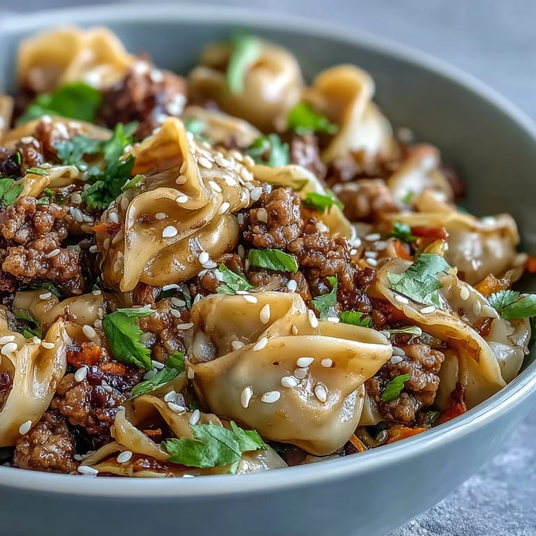 Potsticker Noodle Bowls served with lime wedges and fresh herbs, showcasing saucy noodles and colorful vegetables in a skillet.