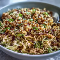 Creamy Potsticker Noodle Stir-Fry with ground turkey and ramen on a ceramic plate, garnished with scallions and sesame seeds for an Asian-inspired meal.