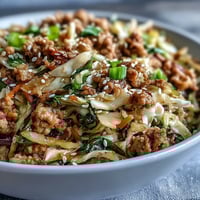 Keto Egg Roll in a Bowl mit Truthahn, Sesamöl und frisch gehacktem Ingwer wird im Wok angerichtet.